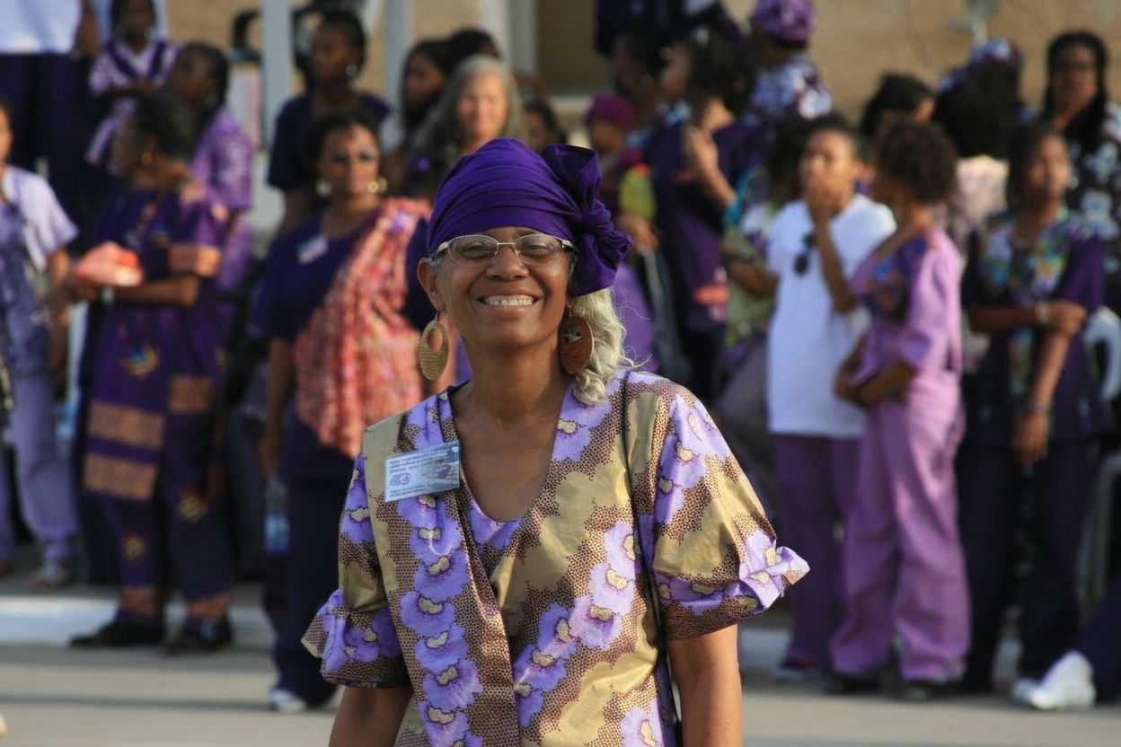 Woman in purple headwrap and radiant smile — everyday joy in the Village of Peace