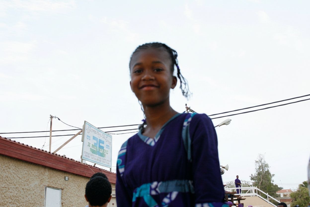 Young girl in purple dress with braids — childhood in the Village of Peace