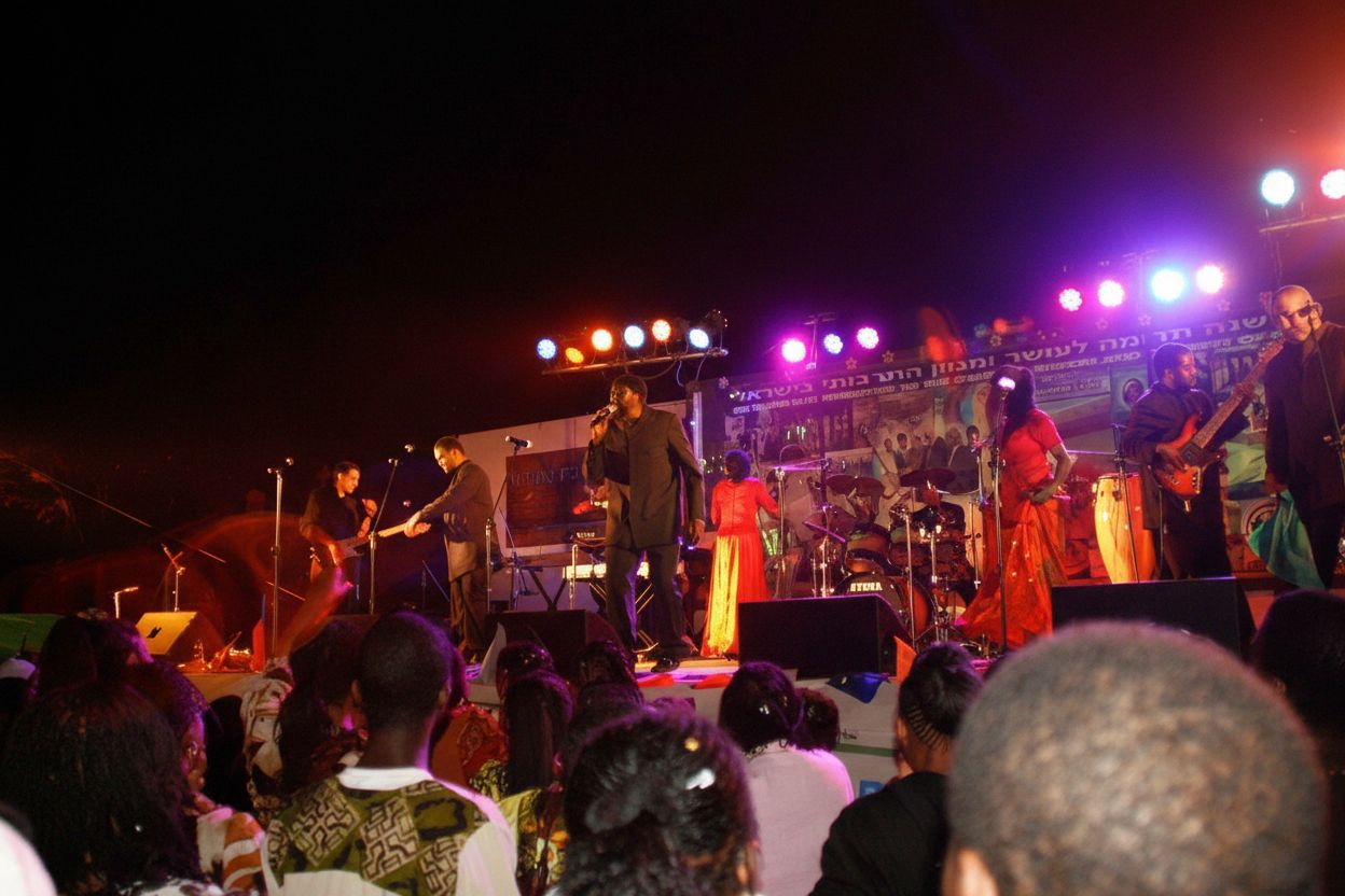 Full band performing at a night celebration with crowd — communal musical energy
