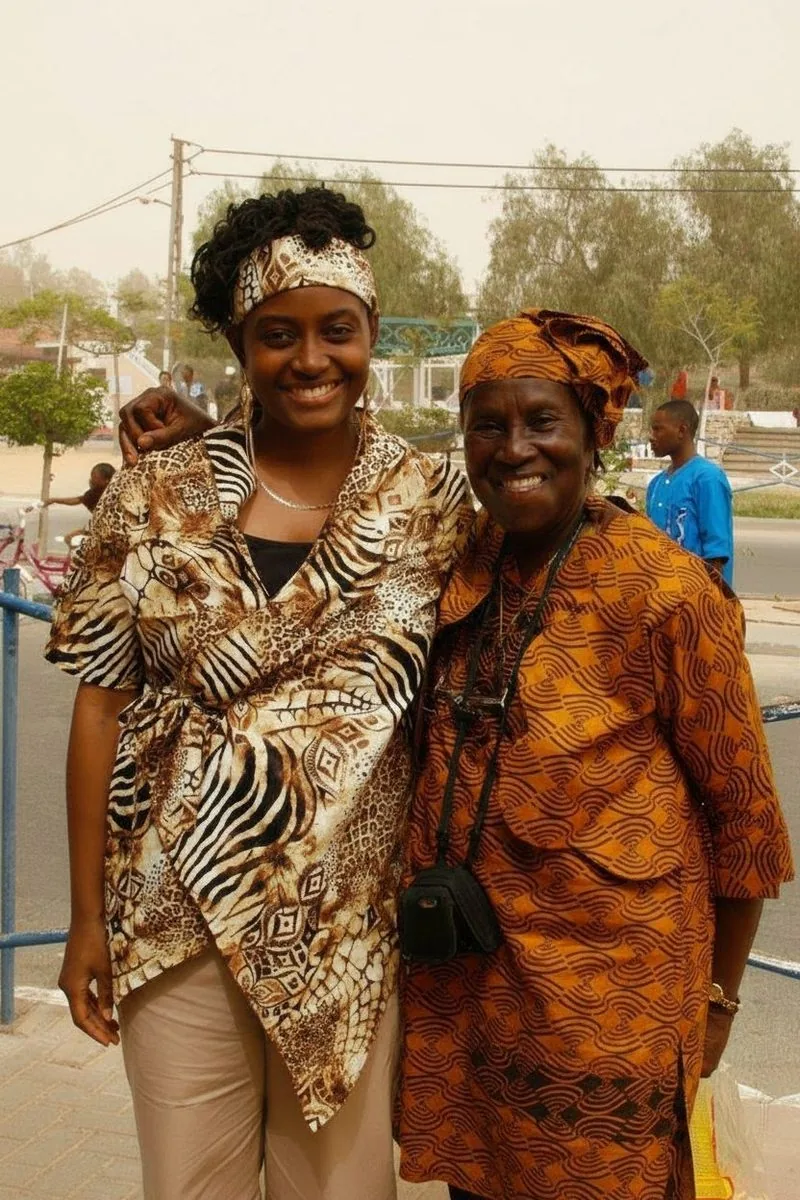 Two women in complementary African-print garments, sharing a moment of community