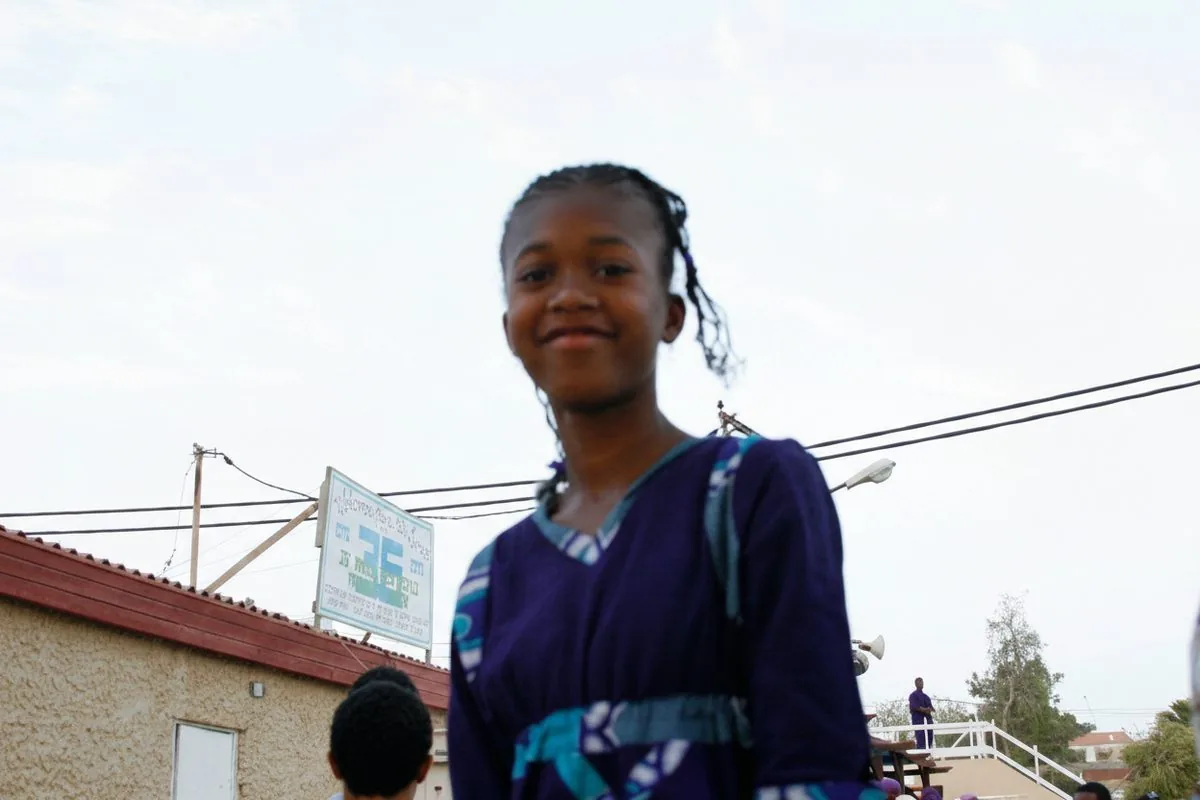 Young girl in purple dress with braids, childhood in the Village of Peace