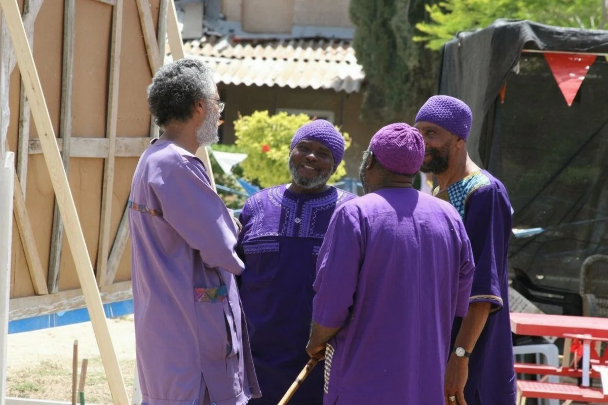 Three men in purple garments in deep conversation at a community gathering
